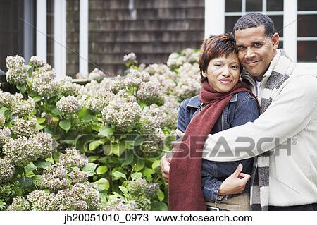 Young couple smiling for the camera outdoors View Large Photo Image Stock Image - Young couple smiling for the camera outdoors. Fotosearch