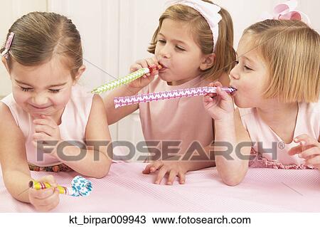 Young girls blowing party favors at their friend View Large Photo Image Stock Image - Young girls blowing party favors at their friend. Fotosearch