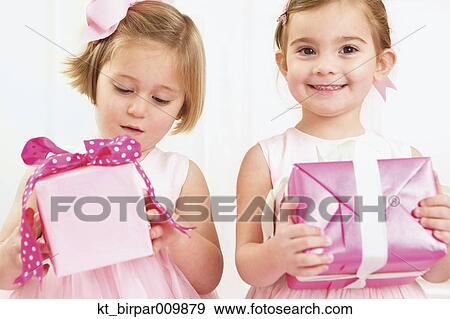 Young girls holding wrapped presents View Large Photo Image Stock Photo - Young girls holding wrapped presents. Fotosearch