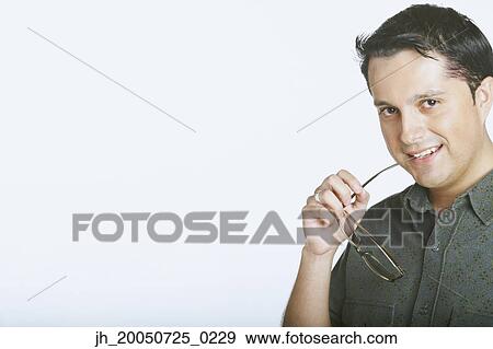 Young man biting the ends of his glasses View Large Photo Image Stock Photo - Young man biting the ends of his glasses. Fotosearch