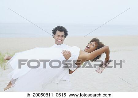 Young man holding his girlfriend on the beach View Large Photo Image Stock Photography - Young man holding his girlfriend on the beach. Fotosearch