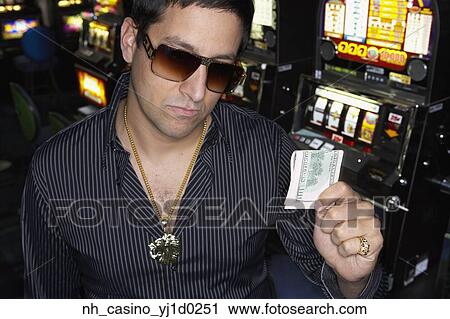 Stock Image - Young man holding his winnings at the casino. Fotosearch