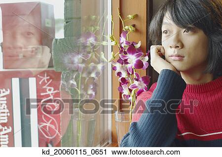 Stock Image - Young man looking out a window. Fotosearch