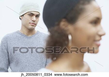 Young man posing for the camera with young woman in foreground View Large Photo Image Picture - Young man posing for the camera with young woman in foreground. Fotosearch