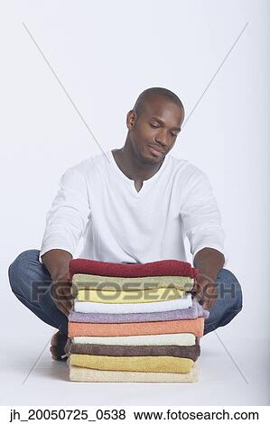Young man posing with a stack of folded towels View Large Photo Image Stock Photo - Young man posing with a stack of folded towels. Fotosearch