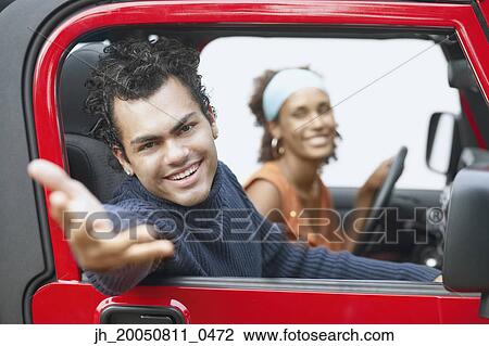 Stock Image - Young man reaching out of car. Fotosearch
