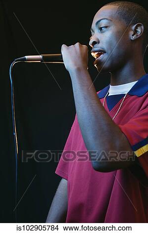 Young man singing into a microphone View Large Photo Image Picture - Young man singing into a microphone. Fotosearch