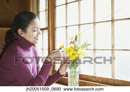 Stock Image - Young woman arranging flowers. Fotosearch