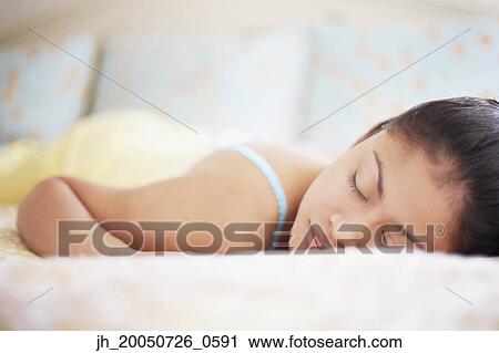 Stock Image - Young woman asleep in bed. Fotosearch