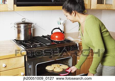 Stock Photo - Young woman chopping fruit in the kitchen. Fotosearch