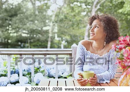 Young woman drinking a cup of coffee outdoors View Large Photo Image Stock Photo - Young woman drinking a cup of coffee outdoors. Fotosearch