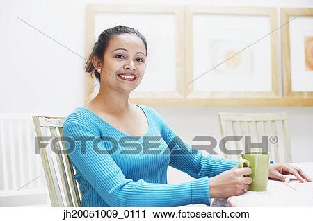 Stock Image - Young woman having a cup of coffee. Fotosearch