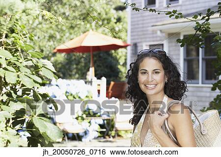 Young woman holding a bag and smiling for the camera View Large Photo Image Stock Photograph - Young woman holding a bag and smiling for the camera. Fotosearch
