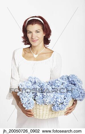 Young woman holding a basket of flowers View Large Photo Image Stock Image - Young woman holding a basket of flowers. Fotosearch