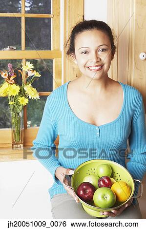 Stock Photograph - Young woman holding a bowl of fruit. Fotosearch