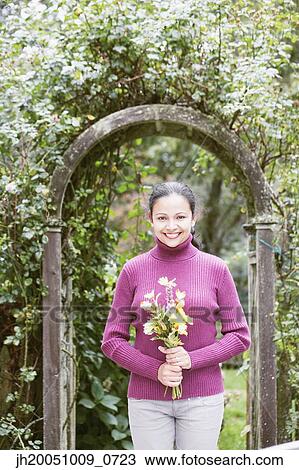 Stock Image - Young woman holding a bunch of flowers. Fotosearch