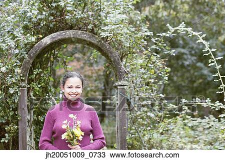 Stock Image - Young woman holding a bunch of flowers. Fotosearch