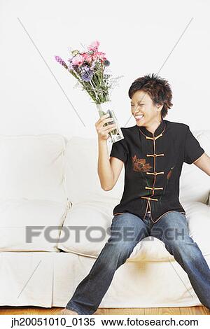 Stock Photography - Young woman holding a vase of flowers. Fotosearch