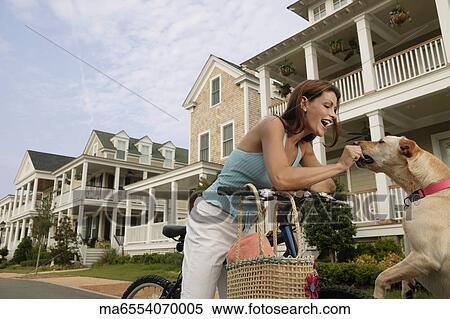 Young woman on a bike giving her dog a treat View Large Photo Image Stock Photography - Young woman on a bike giving her dog a treat. Fotosearch