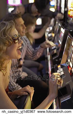 Stock Photo - Young woman playing the slot machines in a casino. Fotosearch