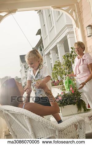 Young woman playing with son in wicker chair View Large Photo Image Stock Photography - Young woman playing with son in wicker chair. Fotosearch