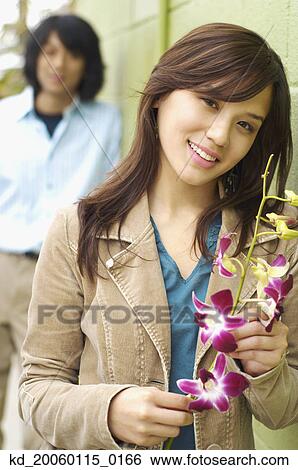 Stock Photograph - Young woman posing for the camera with flowers. Fotosearch