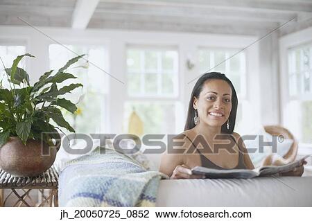 Stock Image - Young woman reading a magazine. Fotosearch