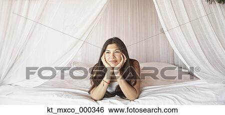 Young woman relaxing in a four-poster bed View Large Photo Image Stock Photograph - Young woman relaxing in a four-poster bed. Fotosearch