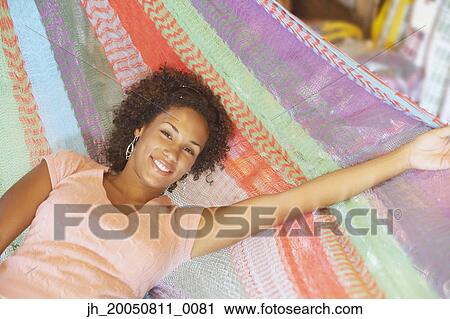 Stock Image - Young woman relaxing in a hammock. Fotosearch