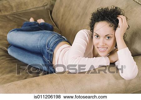 Young woman relaxing on a couch View Large Photo Image Stock Photo - Young woman relaxing on a couch. Fotosearch
