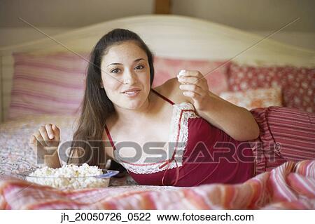 Stock Image - Young woman relaxing on her bed. Fotosearch