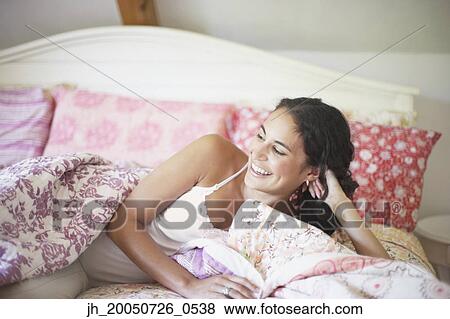 Young woman relaxing on her bed View Large Photo Image Stock Photo - Young woman relaxing on her bed. Fotosearch