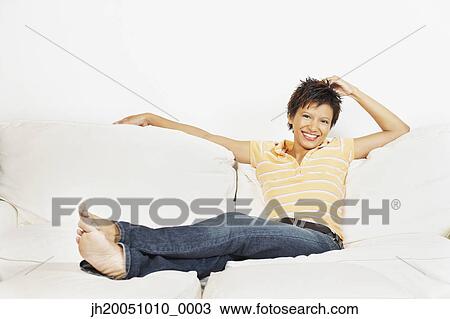 Stock Image - Young woman relaxing on the couch. Fotosearch
