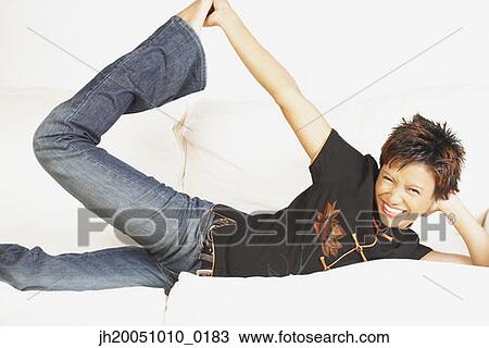 Stock Image - Young woman relaxing on the couch. Fotosearch