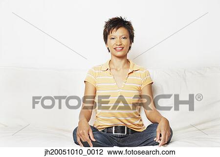 Young woman sitting cross-legged on the couch View Large Photo Image Stock Image - Young woman sitting cross-legged on the couch. Fotosearch
