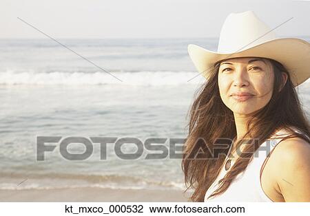 Young woman smiling for the camera at the beach View Large Photo Image Stock Image - Young woman smiling for the camera at the beach. Fotosearch