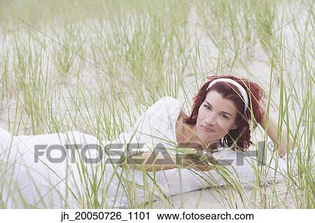 Young woman smiling for the camera on the beach View Large Photo Image Stock Image - Young woman smiling for the camera on the beach. Fotosearch