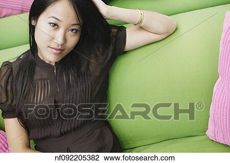 Young woman smiling for the camera on couch View Large Photo Image Stock Image - Young woman smiling for the camera on couch. Fotosearch