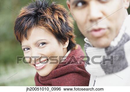 Young woman smiling for the camera beside her boyfriend View Large Photo Image Stock Photograph - Young woman smiling for the camera beside her boyfriend. Fotosearch