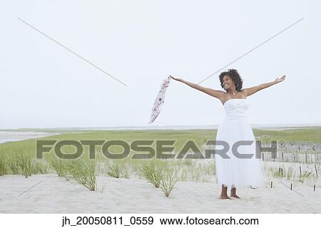 Young woman standing on the beach with her arms outstretched View Large Photo Image Stock Photo - Young woman standing on the beach with her arms outstretched. Fotosearch