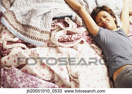 Young woman stretching in bed View Large Photo Image Stock Image - Young woman stretching in bed. Fotosearch