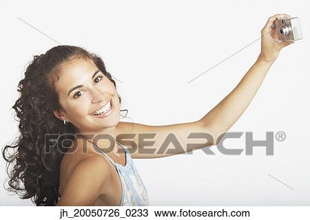 Young woman taking a picture of herself using a digital camera View Large Photo Image Stock Image - Young woman taking a picture of herself using a digital camera. Fotosearch