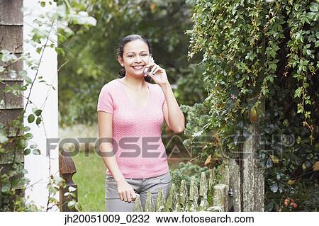 Young woman talking on her cell phone outdoors View Large Photo Image Stock Image - Young woman talking on her cell phone outdoors. Fotosearch