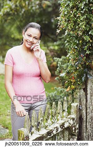 Young woman talking on her cell phone outdoors View Large Photo Image Stock Photograph - Young woman talking on her cell phone outdoors. Fotosearch
