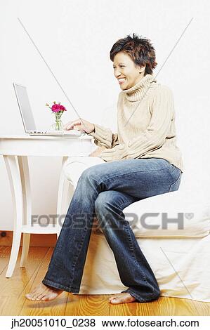 Young woman using a laptop View Large Photo Image Stock Photo - Young woman using a laptop. Fotosearch