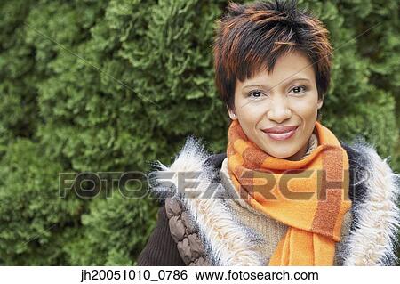 Stock Photograph - Young woman wearing a scarf and coat outdoors. Fotosearch