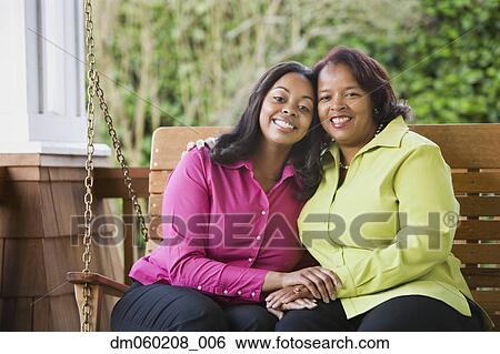 Stock Photograph - Mother and daughter smiling on a porch swing. Fotosearch