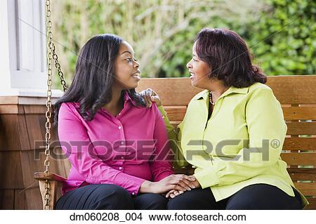 Picture - Mother and daughter talking on a porch swing. Fotosearch