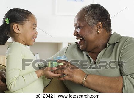 Stock Image - Senior woman giving her granddaughter a gift. Fotosearch