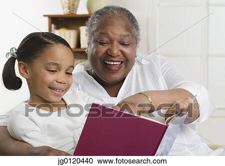 Stock Image - Senior woman reading to her granddaughter. Fotosearch